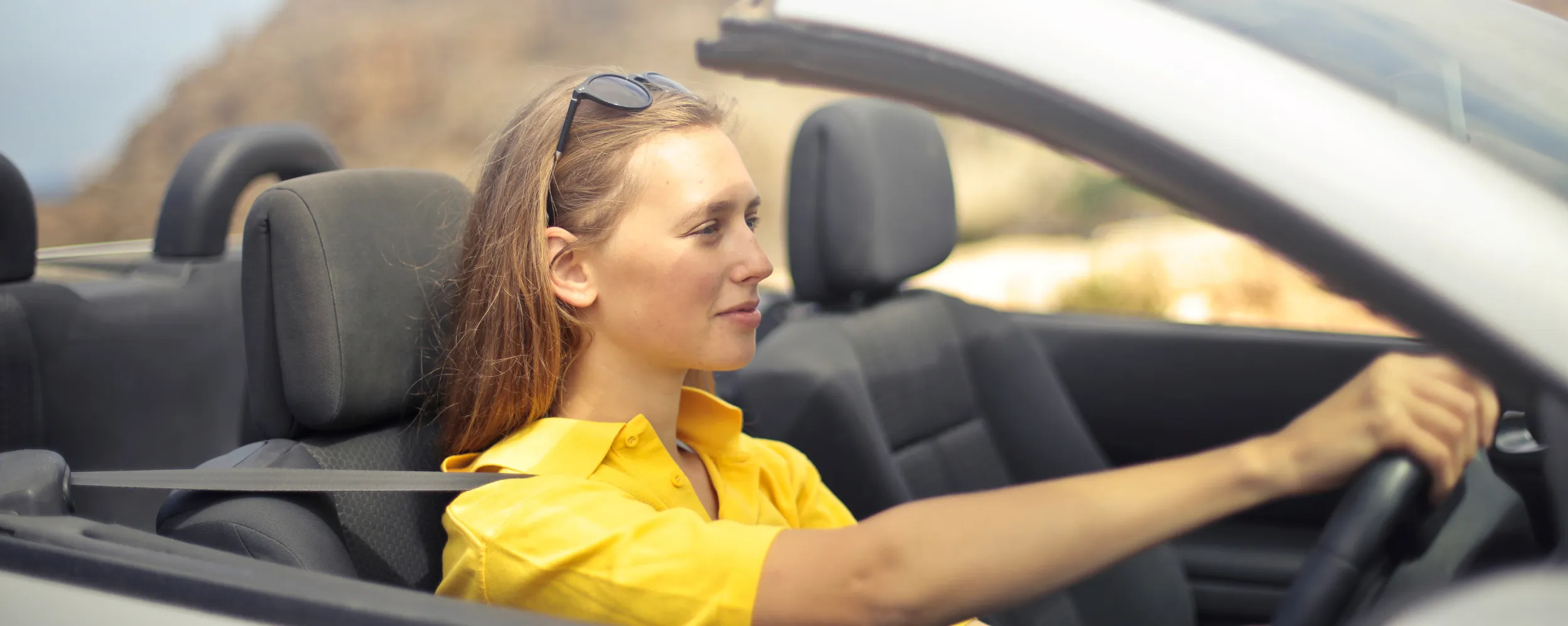 Mujer conduciendo un coche eléctrico convertible amarillo en carretera