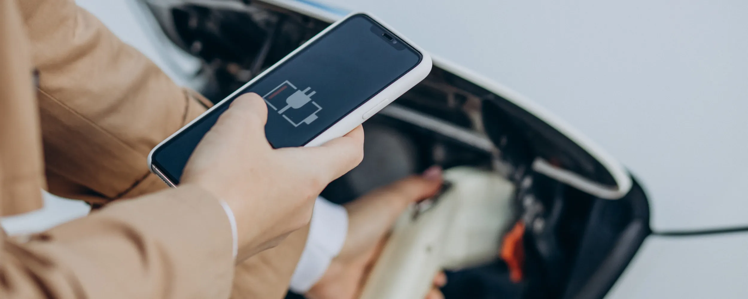Persona cargando un coche eléctrico mediante aplicación móvil