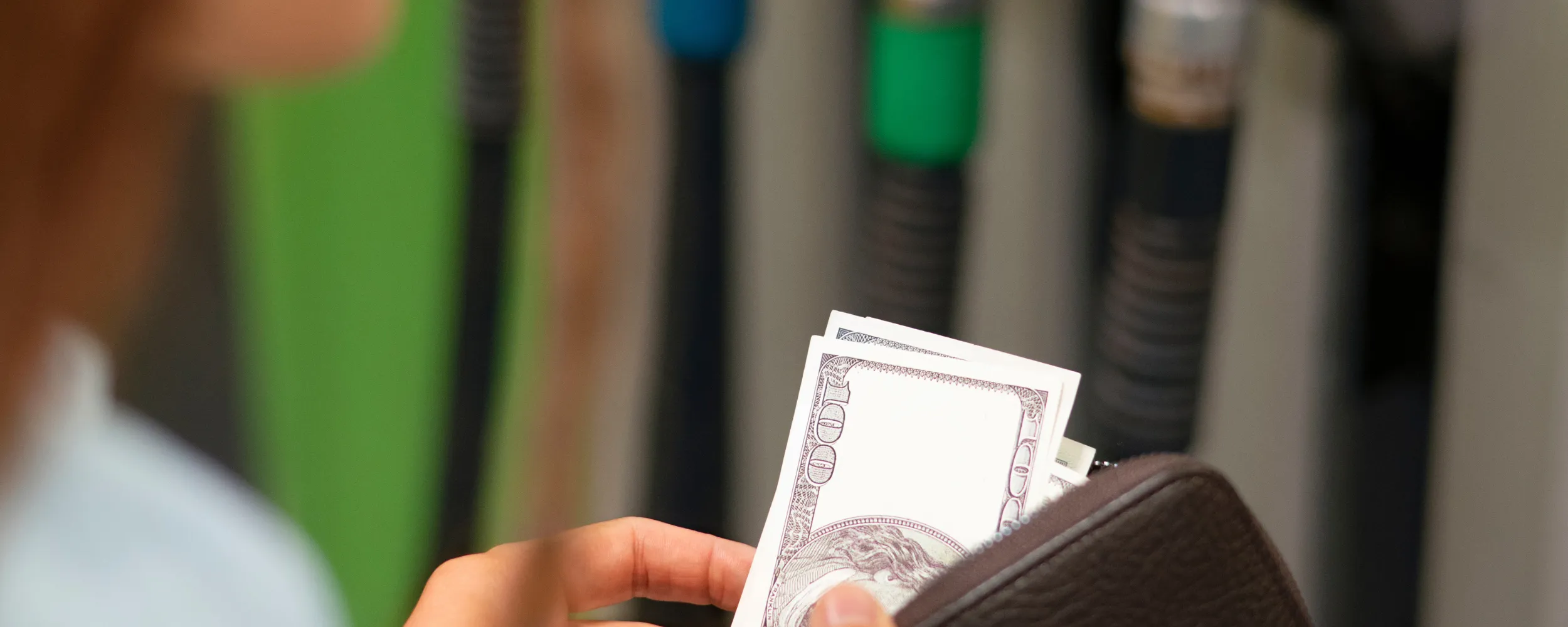 Persona mostrando un billete de dólar en una cartera, simbolizando el ahorro económico