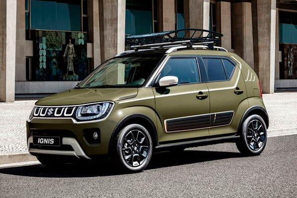 Suzuki Ignis verde oliva con baca y llantas negras aparcado en una calle urbana frente a un edificio de hormigón