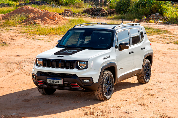 Jeep Renegade blanco con neumáticos de taco sobre un camino de tierra rojiza, con vegetación seca y montículos de arena