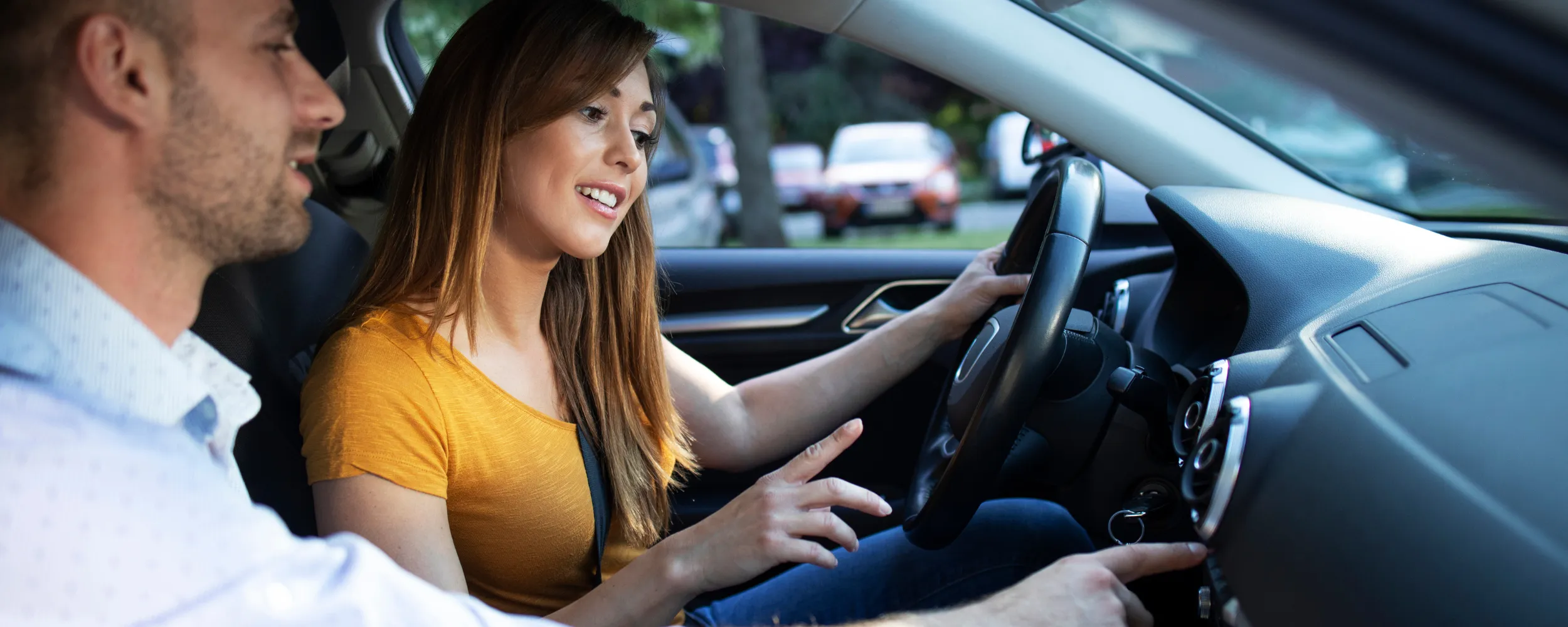 Instructor enseñando a conducir coche automático a alumna durante clase práctica