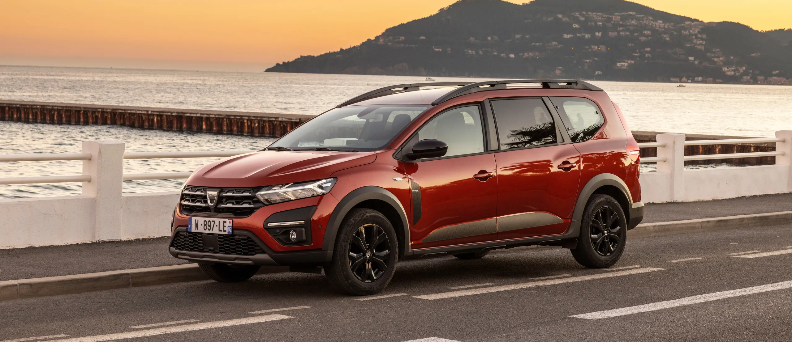 Renault Espace rojo de 7 plazas aparcado en paseo marítimo al atardecer