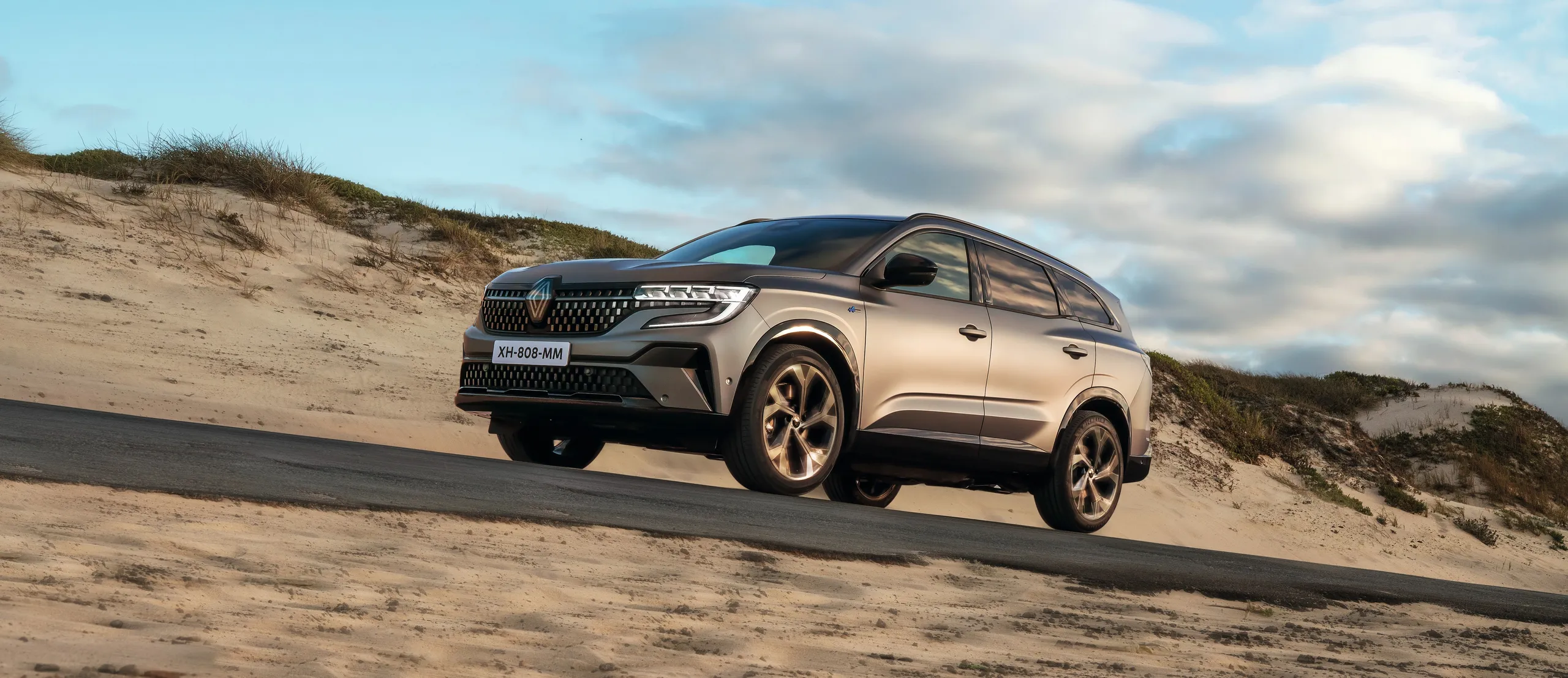 Renault Austral SUV blanco de 7 plazas en carretera costera con dunas