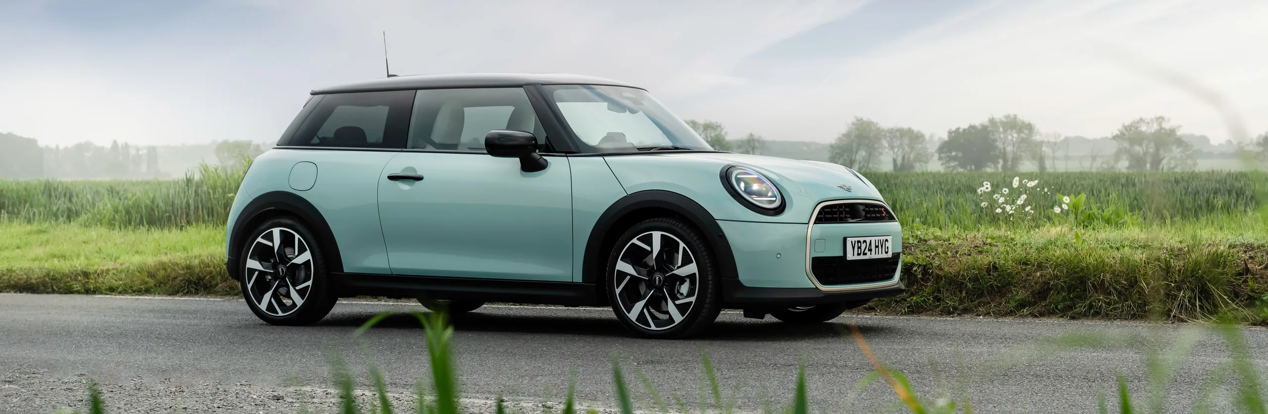 Mini Cooper SE eléctrico azul claro aparcado en carretera rural
