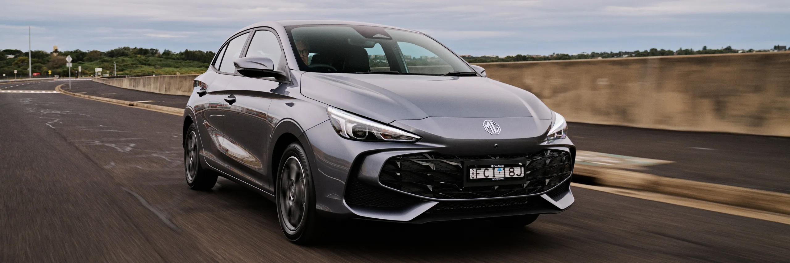 MG3 híbrido gris circulando por autopista con diseño futurista y faros LED