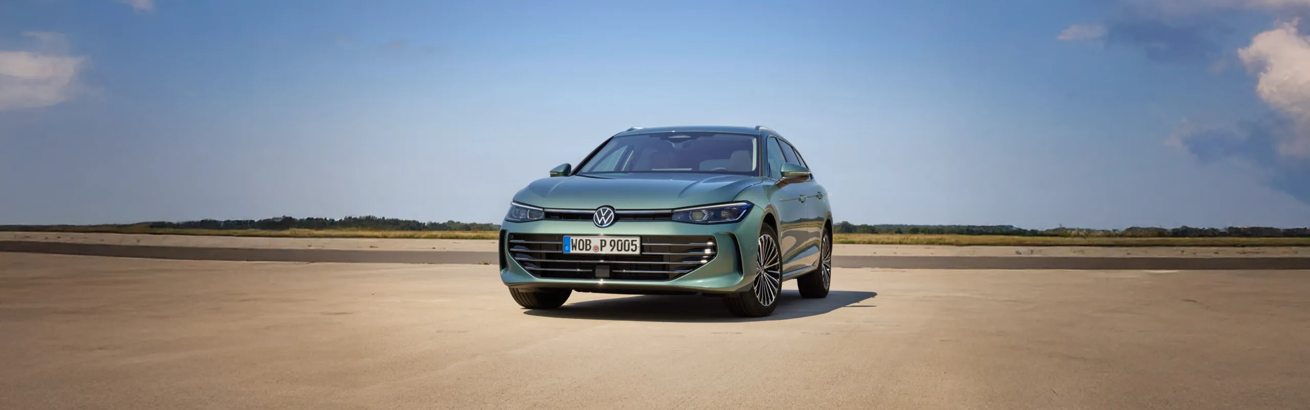 Volkswagen Passat Alltrack gris azulado aparcado en explanada amplia con cielo despejado