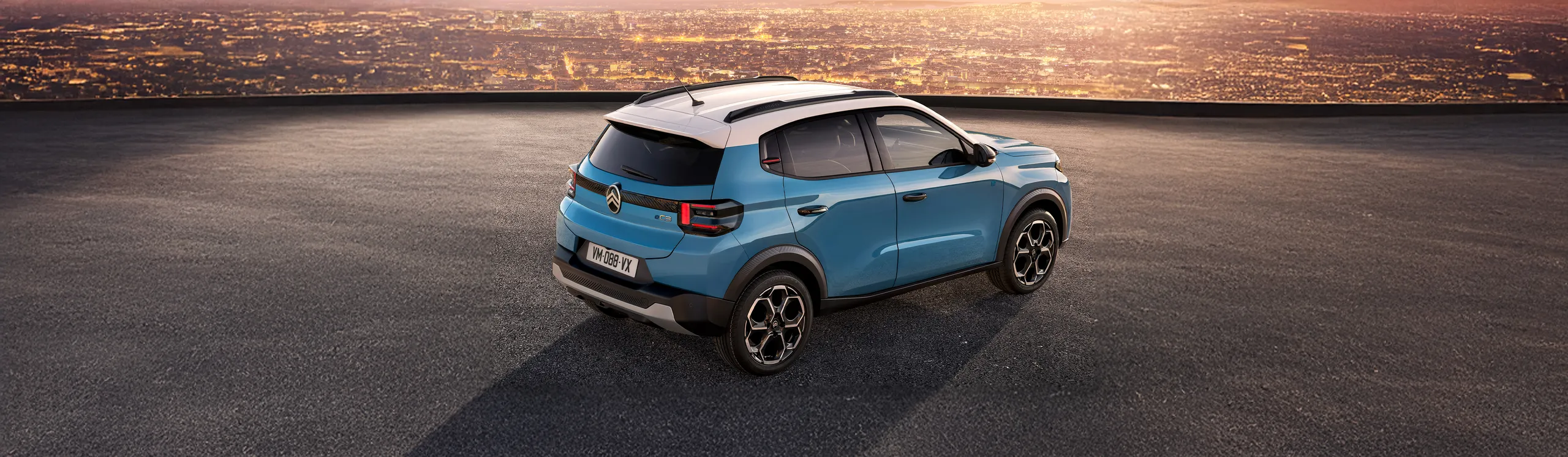 Opel Corsa eléctrico azul claro aparcado en azotea con vistas de ciudad