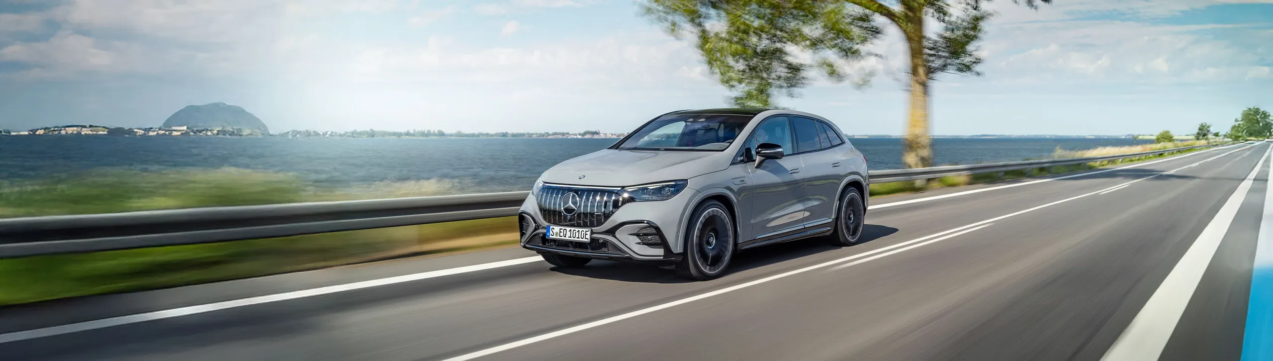 Mercedes-AMG EQE SUV blanco circulando por autopista con paisaje de montaña al fondo
