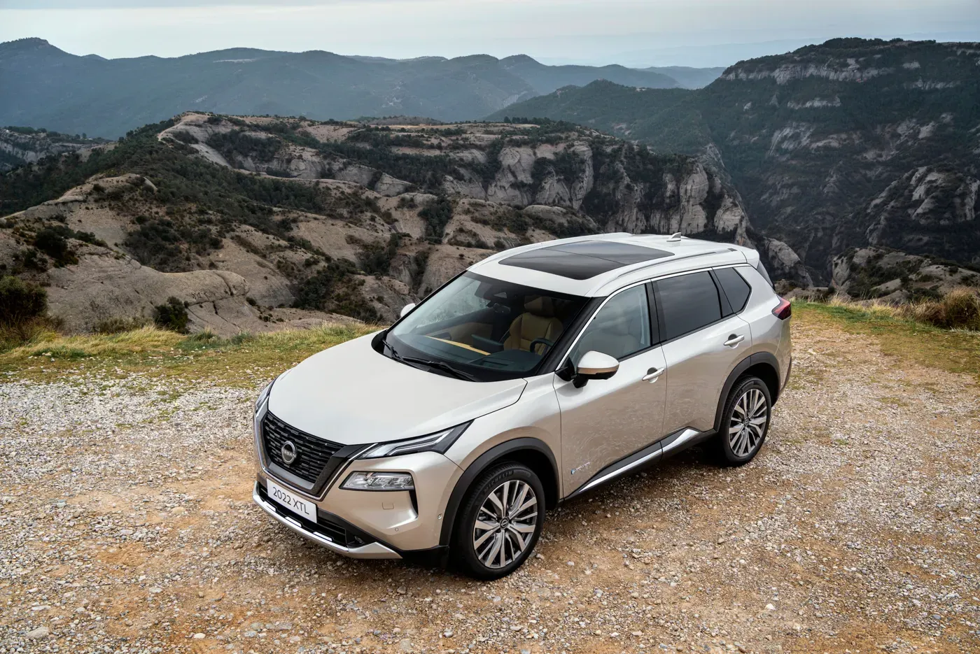 Nissan X-Trail blanco en carretera de montaña con espacioso maletero para viajar