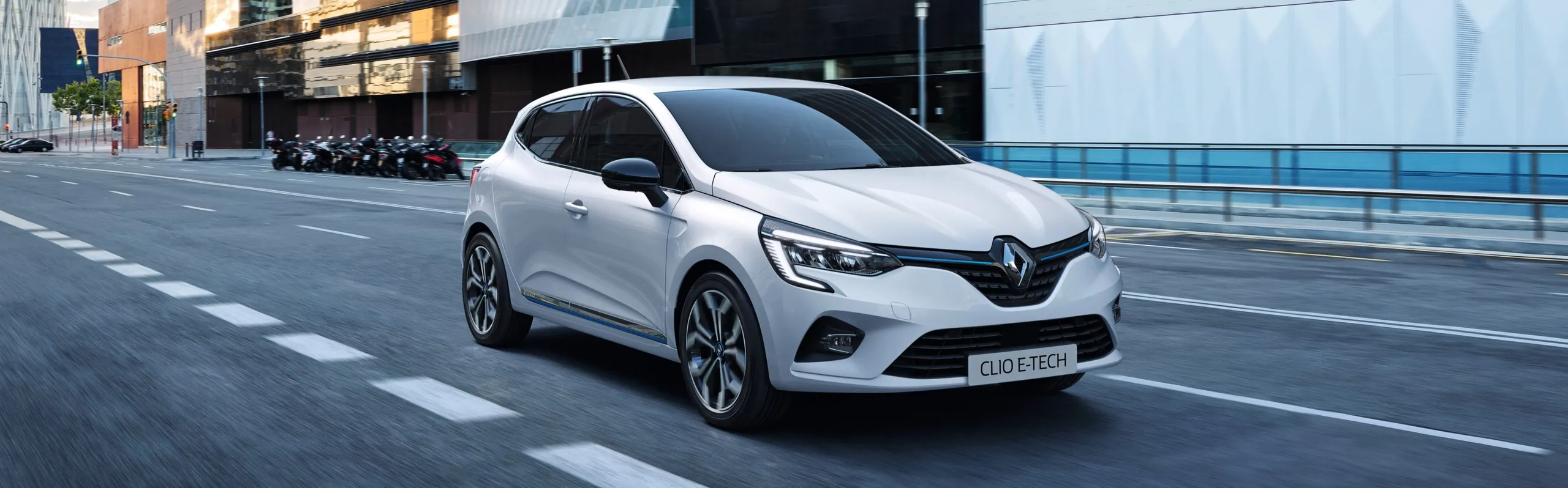 Renault Clio E-Tech híbrido blanco circulando por una calle urbana moderna