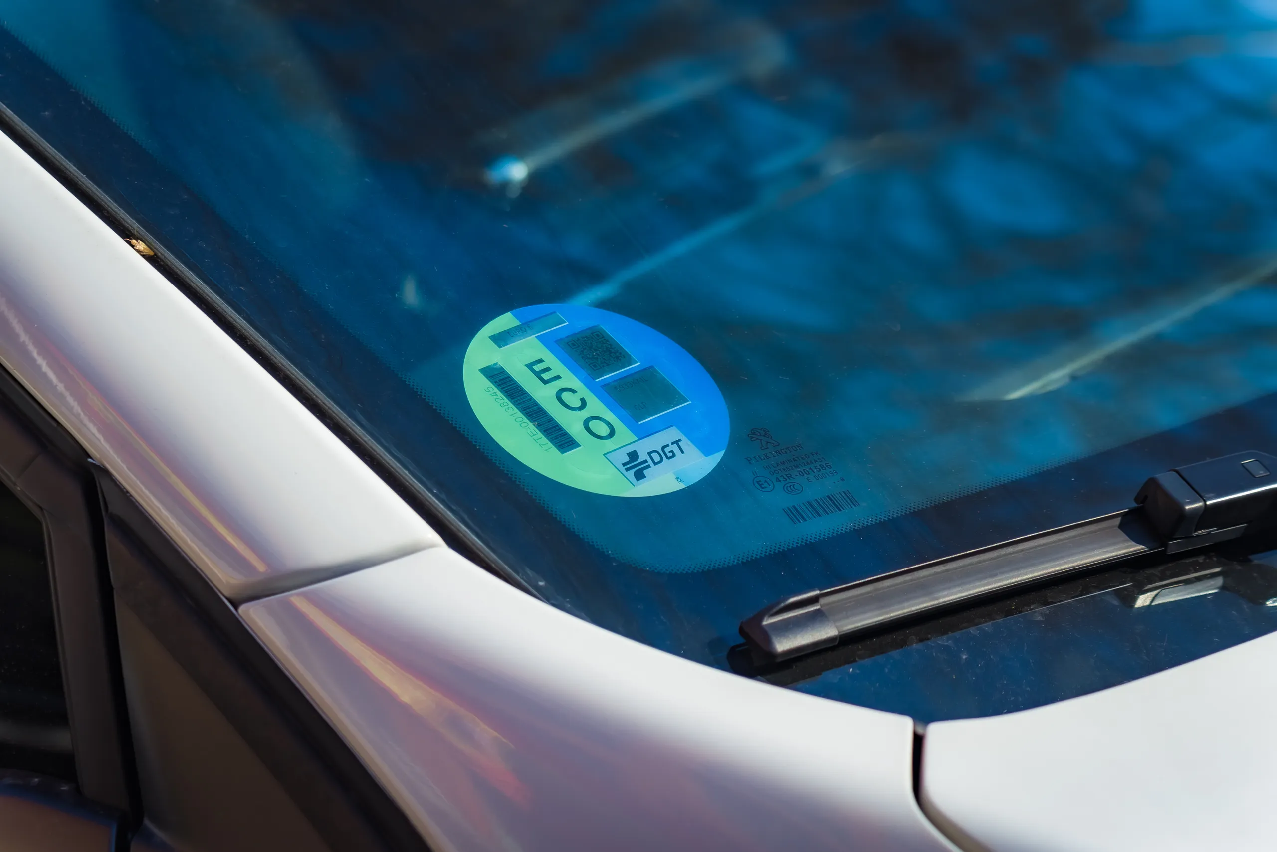Pegatina ECO verde y azul de la DGT en parabrisas de coche blanco