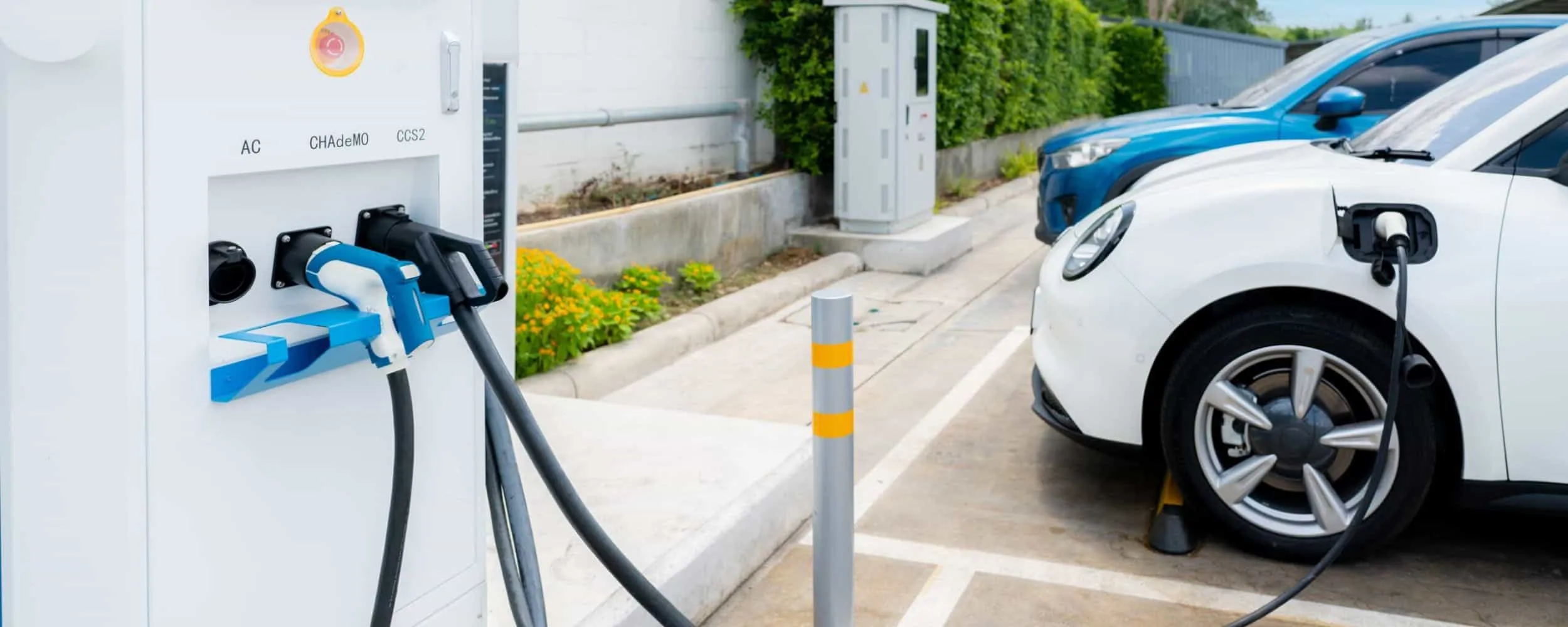 Punto de carga público con cables conectados y coche eléctrico blanco recargando