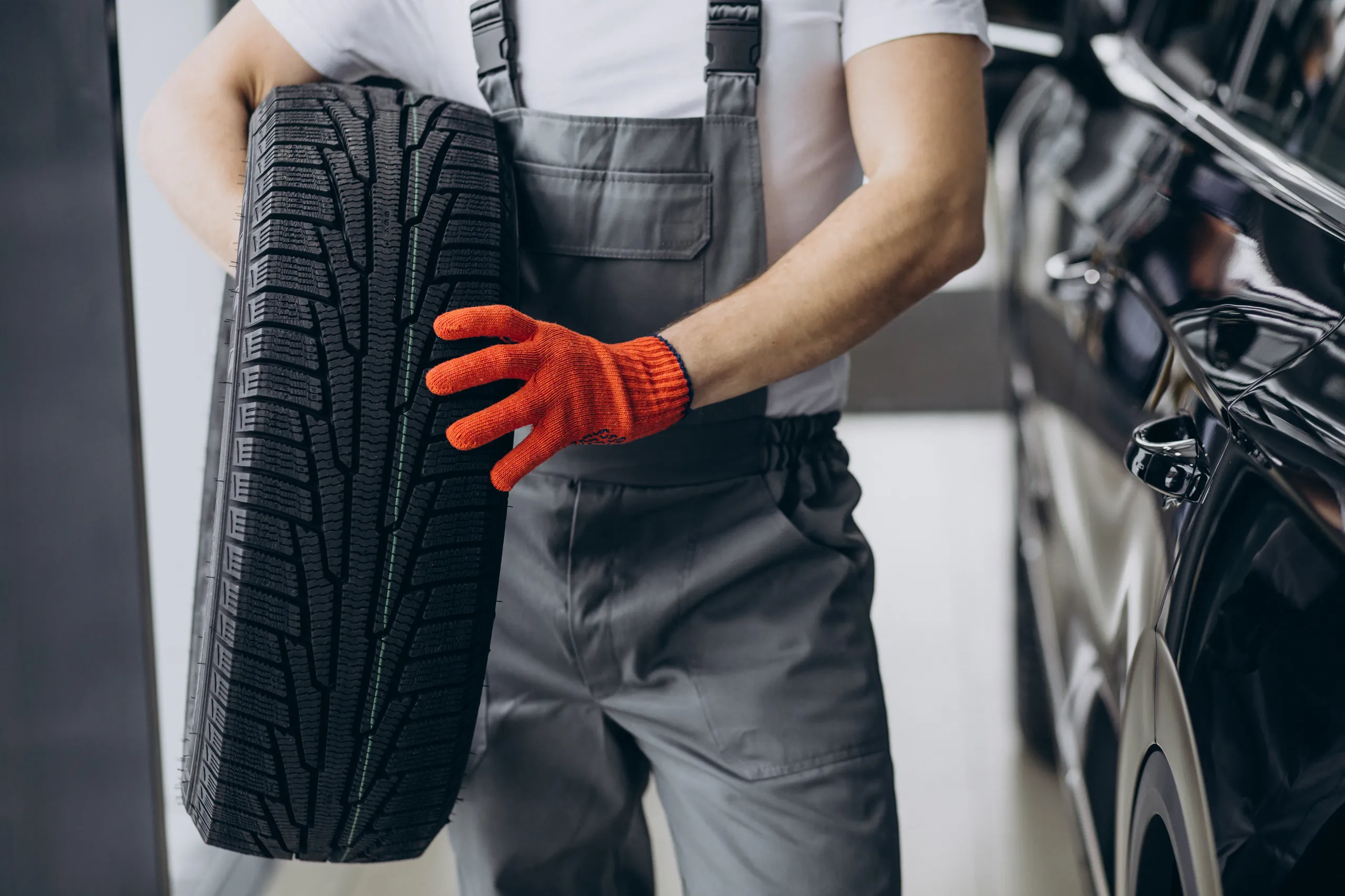Mecánico inspecciona el desgaste de un neumático de invierno con guantes de seguridad