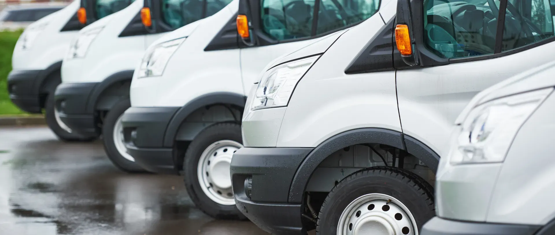 Fila de furgonetas blancas estacionadas para la venta de stock de vehículos