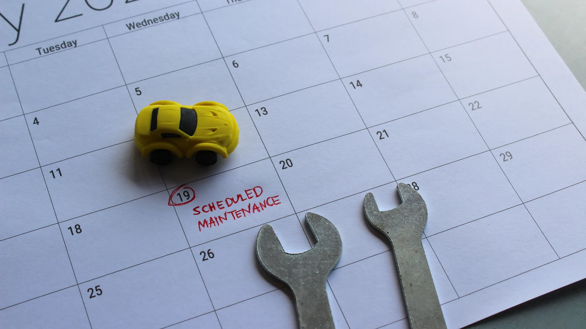 Calendario de mantenimiento programado con coche amarillo y herramientas