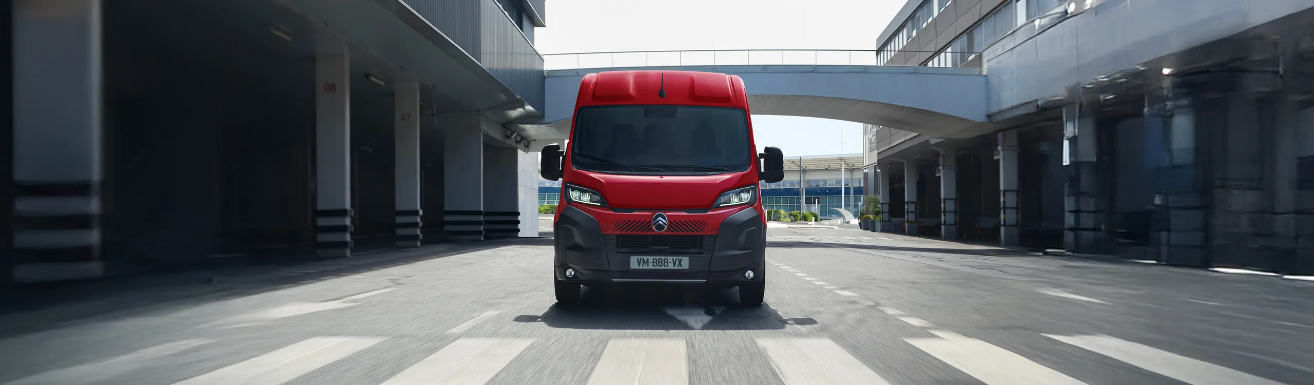 Renault Master roja circulando por una zona urbana moderna con edificios