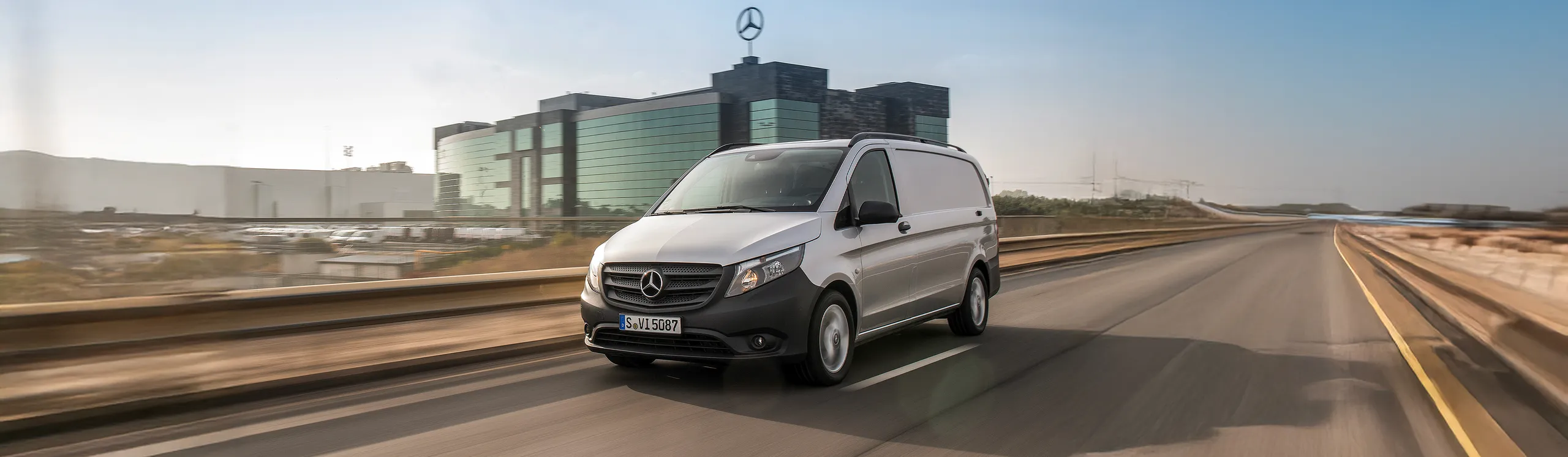 Mercedes-Benz Vito blanca circulando por carretera junto a instalaciones industriales