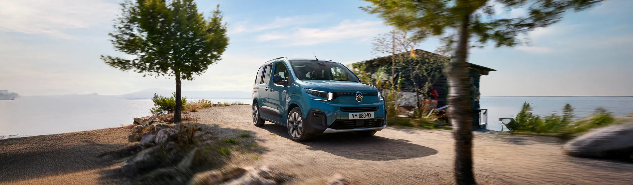 Volkswagen Caddy azul aparcada junto a la playa con vistas al mar