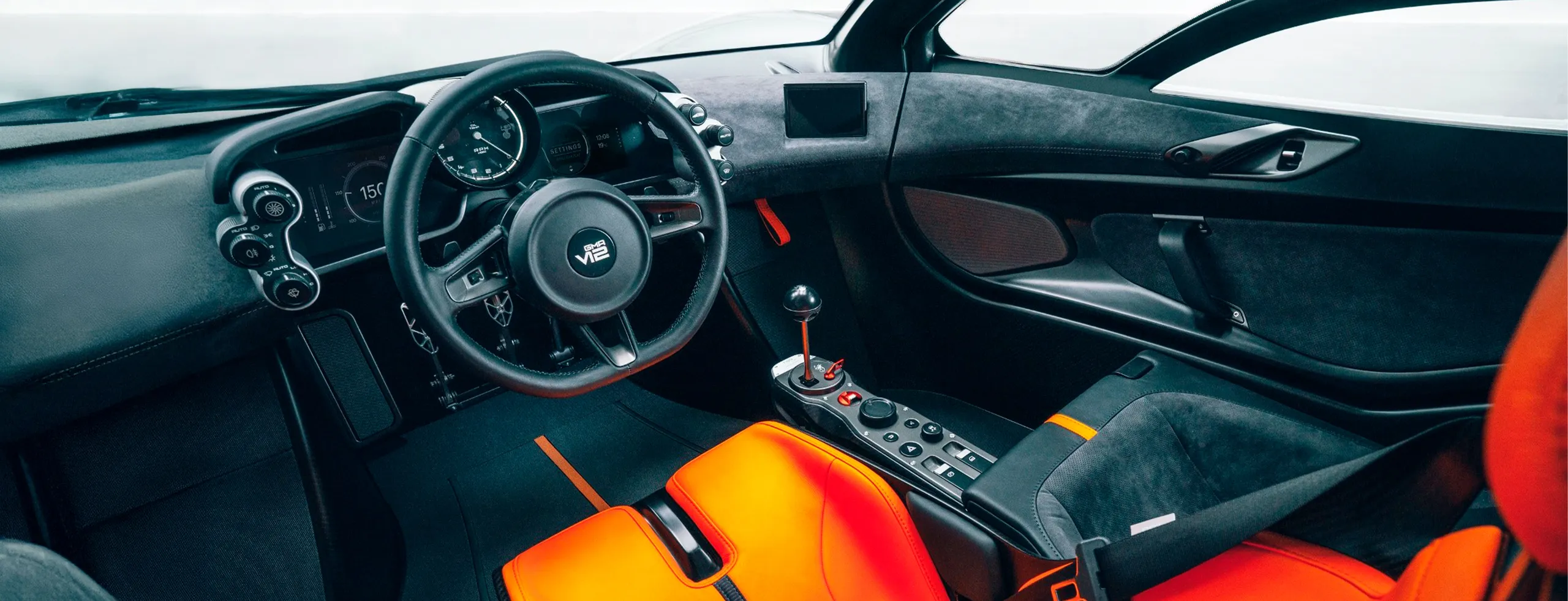 Interior del Gordon Murray T50 con volante deportivo y asientos en naranja y negro