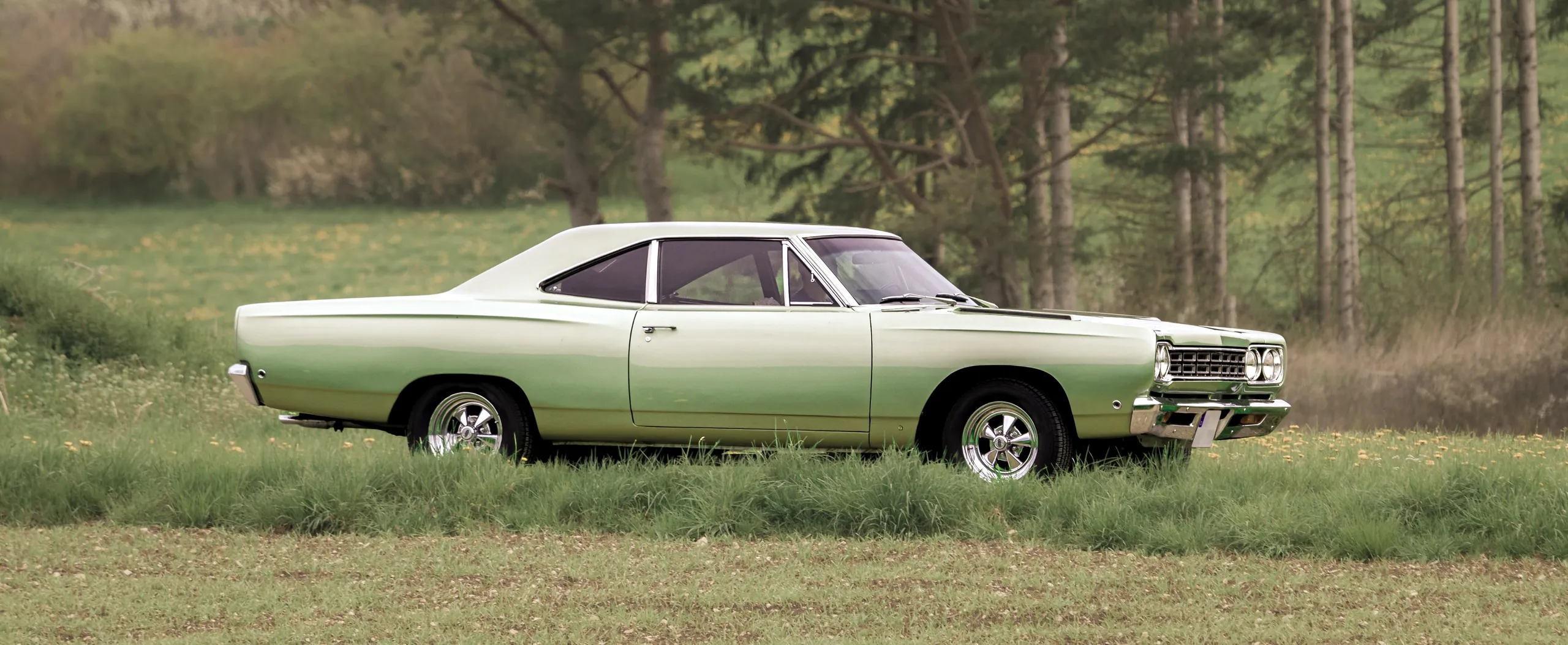 Coche clásico verde y blanco de los años 70 en un campo rural
