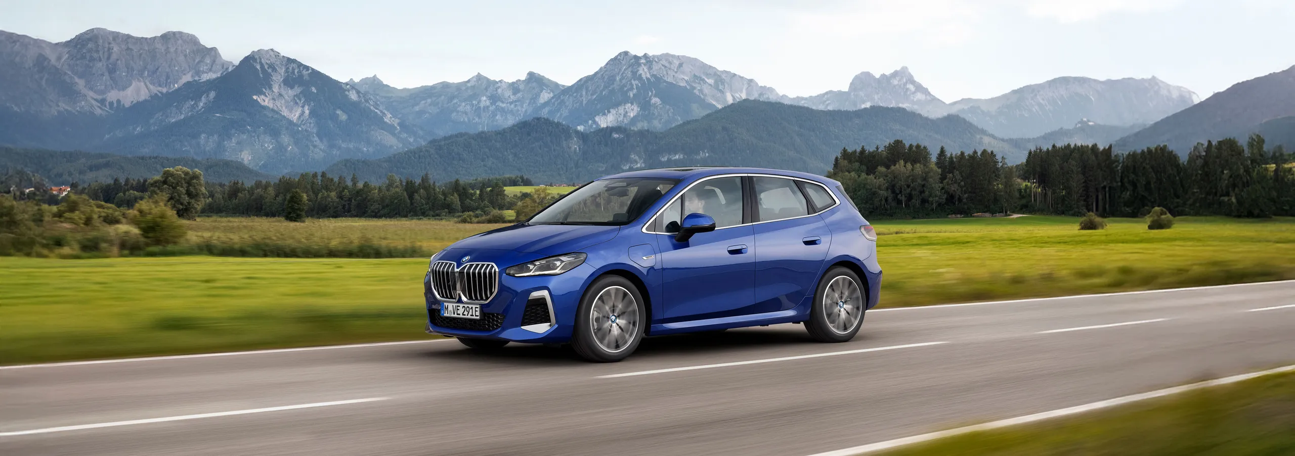 BMW i1 azul híbrido enchufable circulando por carretera con montañas