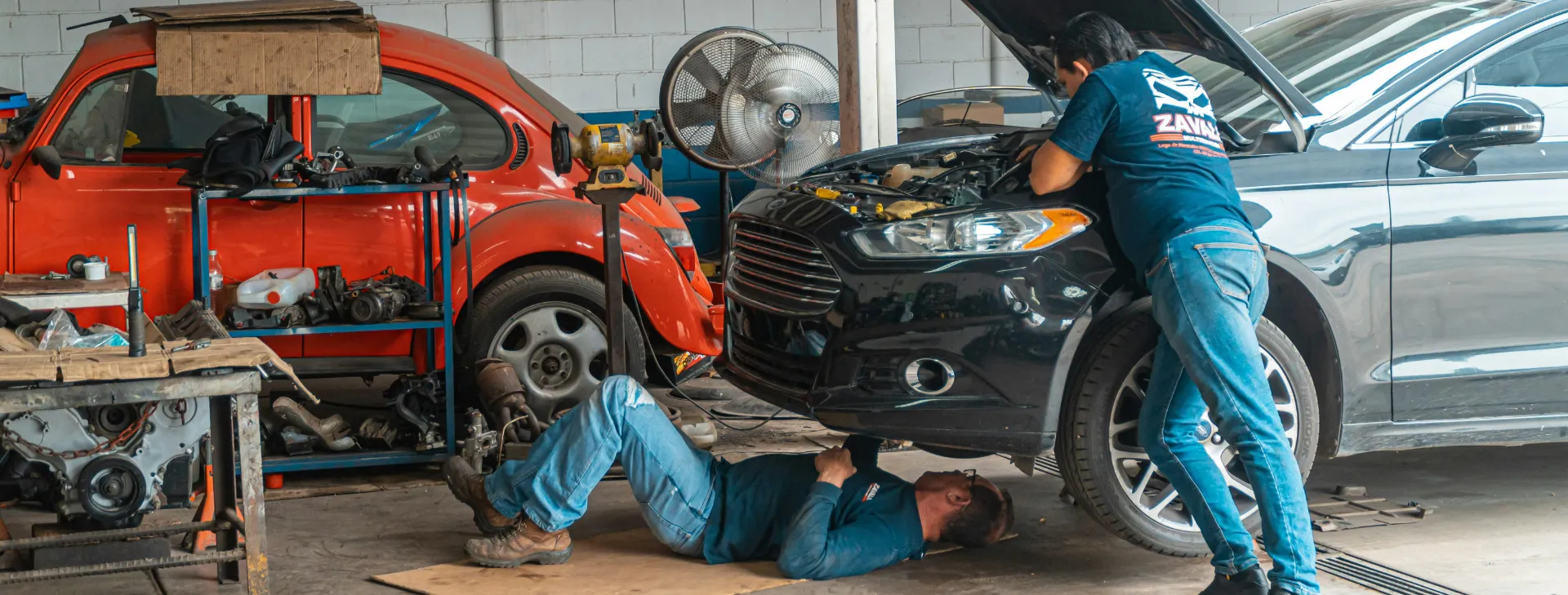 Mecánico reparando el motor de un coche negro en un taller profesional