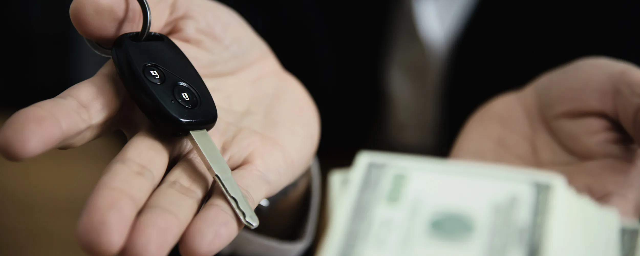 Persona mostrando las llaves de un coche junto a billetes de dinero