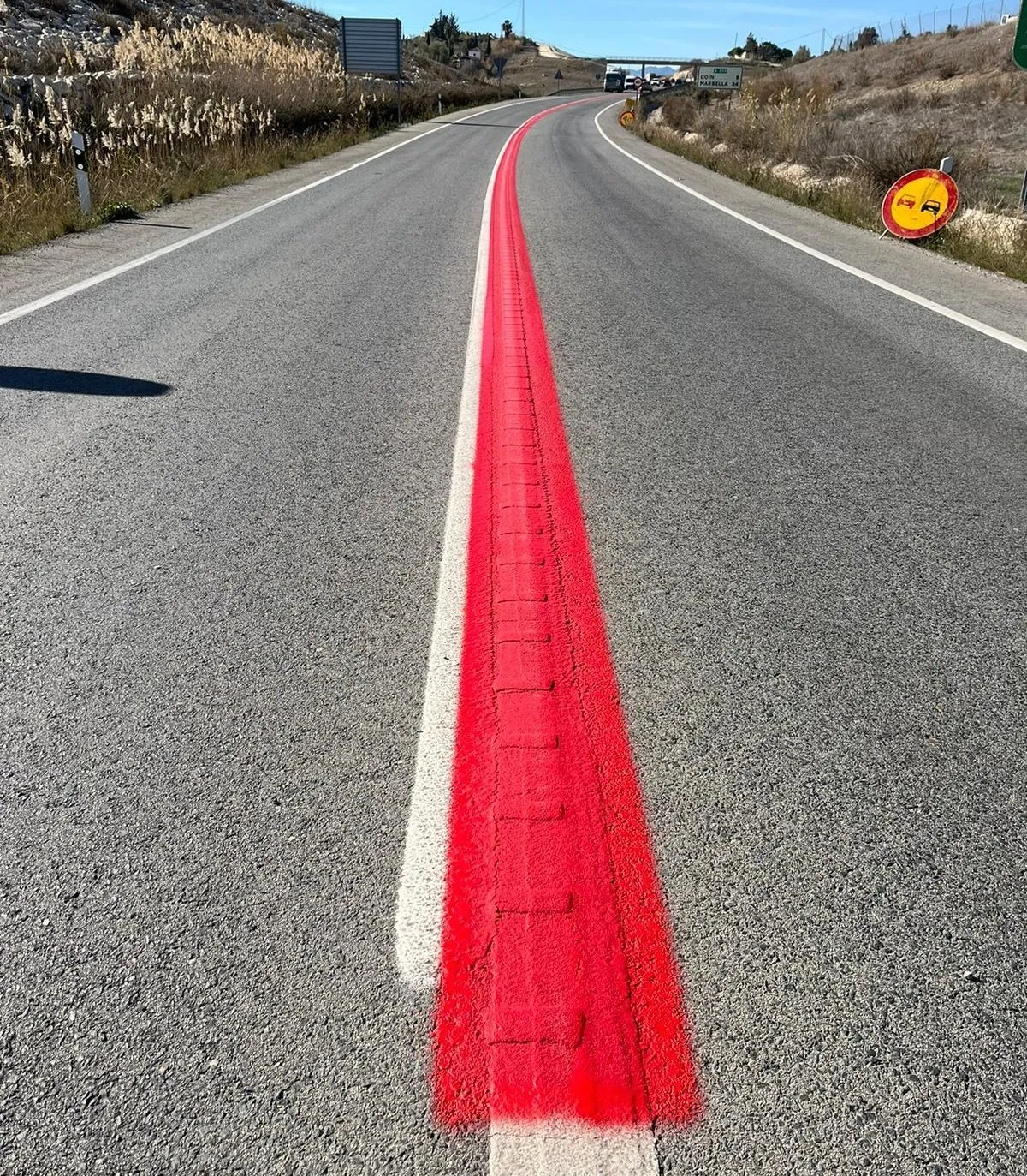 Línea roja continua pintada en carretera sinuosa, indicando zona de peligro