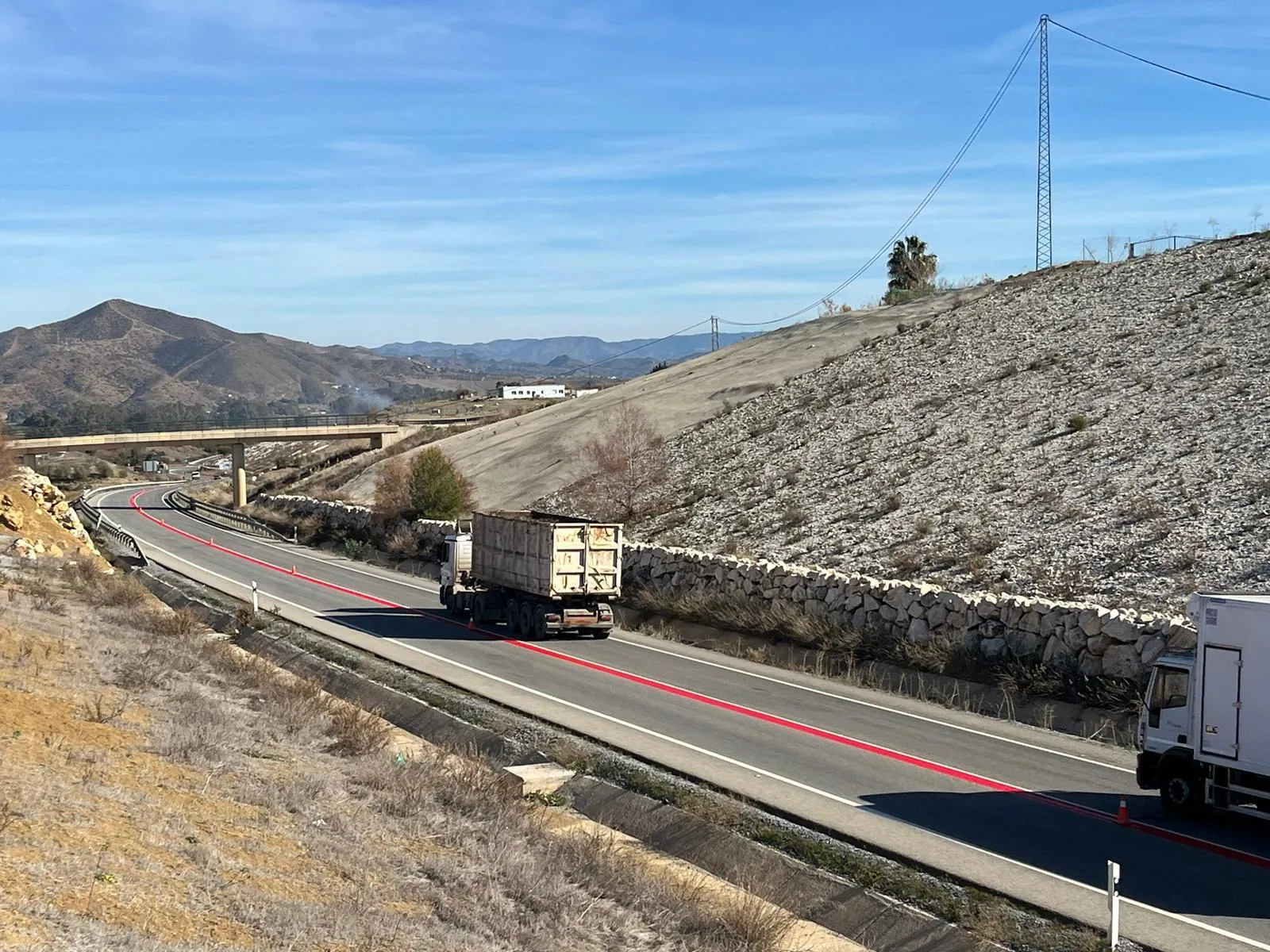 Carretera con línea roja continua en tramo peligroso de montaña con camión