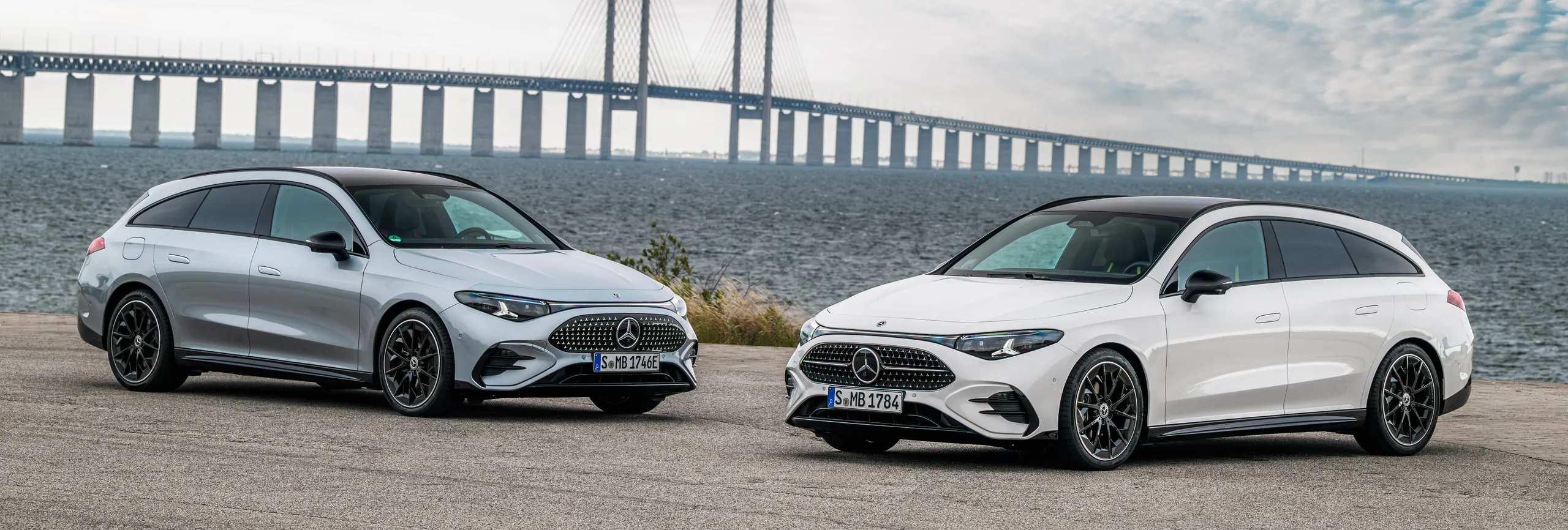 Dos Mercedes-Benz sedán blanco frente al puente de Øresund, símbolo de ingeniería alemana