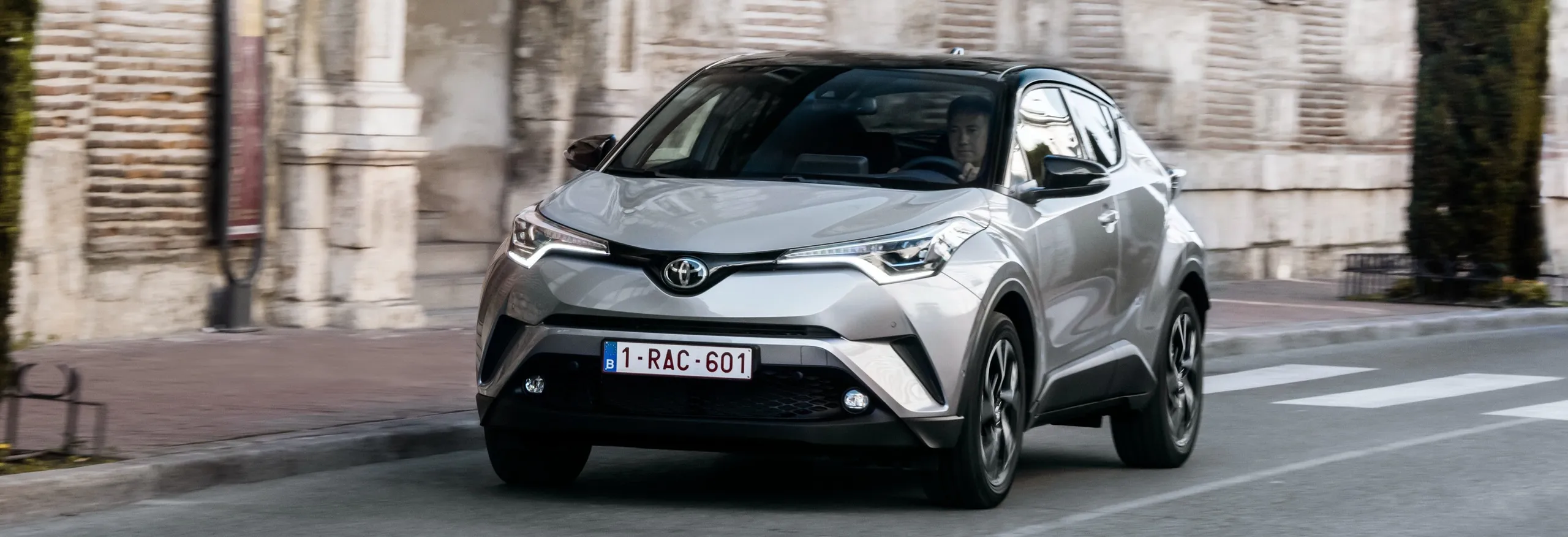 Toyota C-HR blanco circulando por calle urbana con edificios históricos
