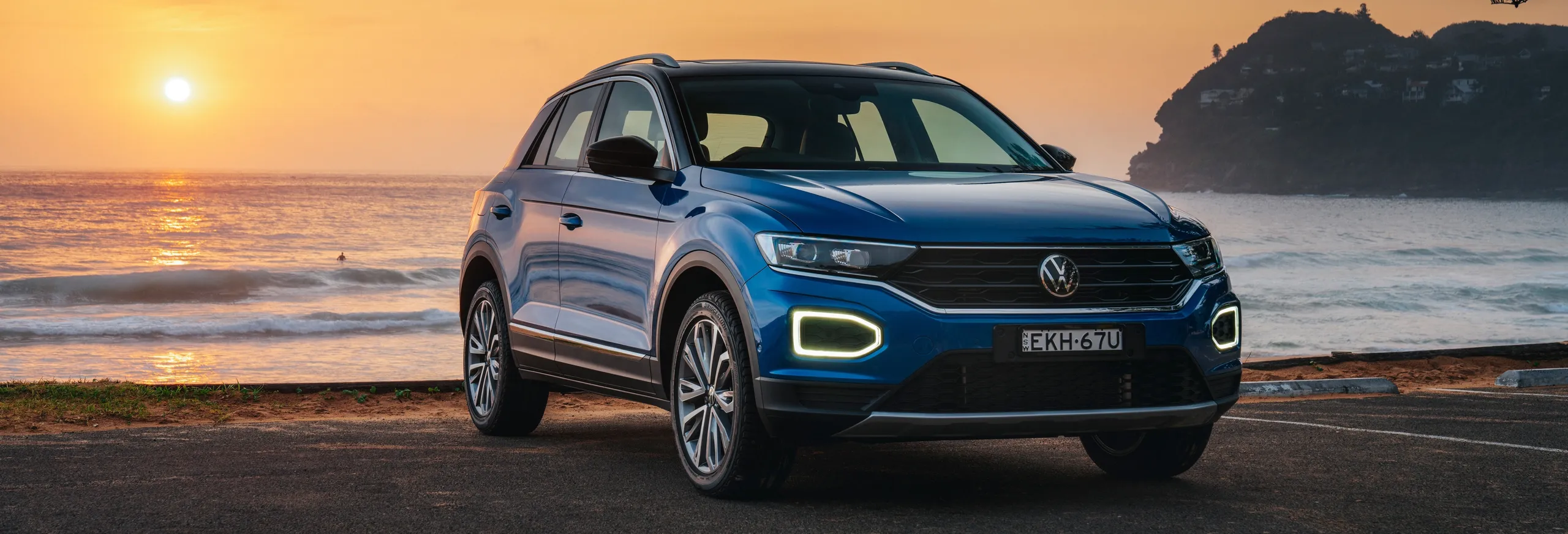 Volkswagen T-Roc azul en atardecer junto al mar, SUV compacto moderno