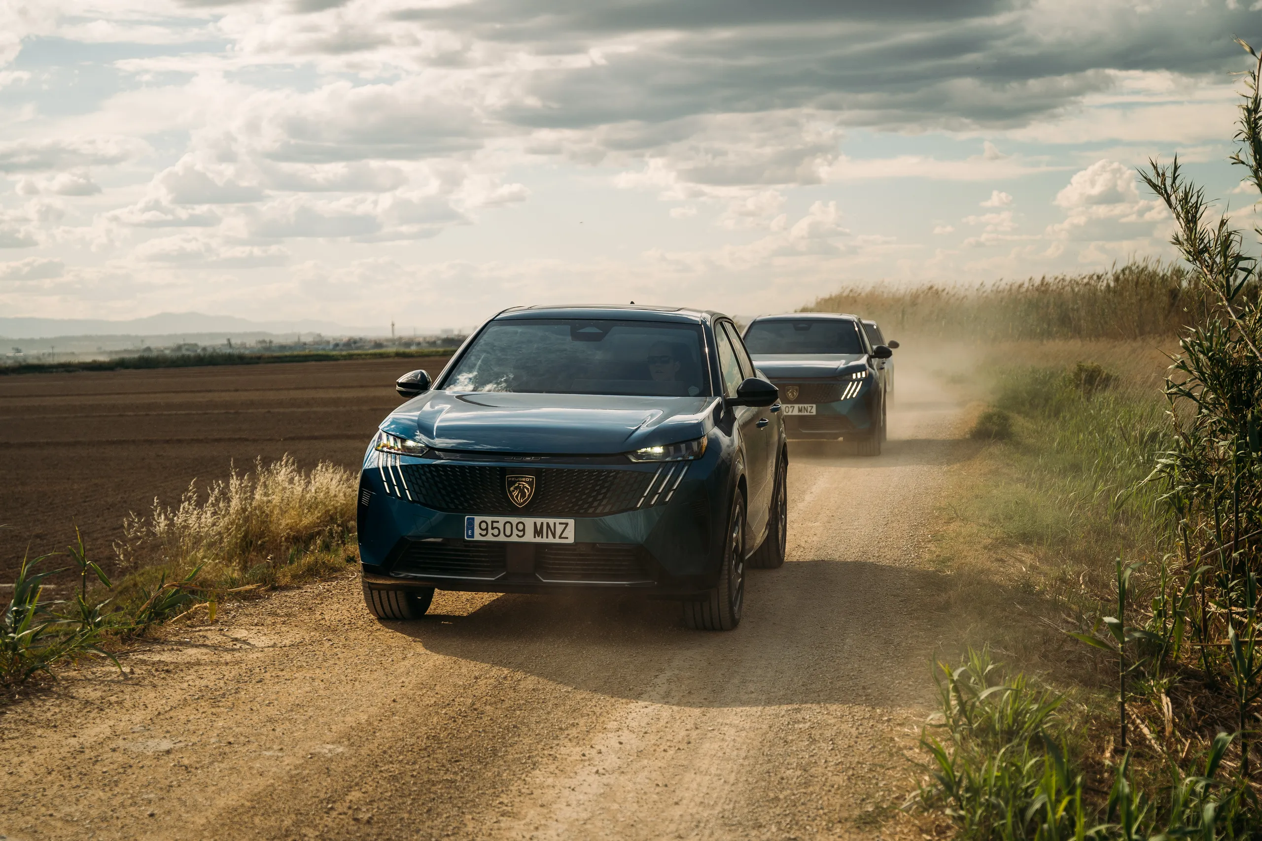 Dos Peugeot 3008 azules circulando por camino de tierra entre campos de cultivo