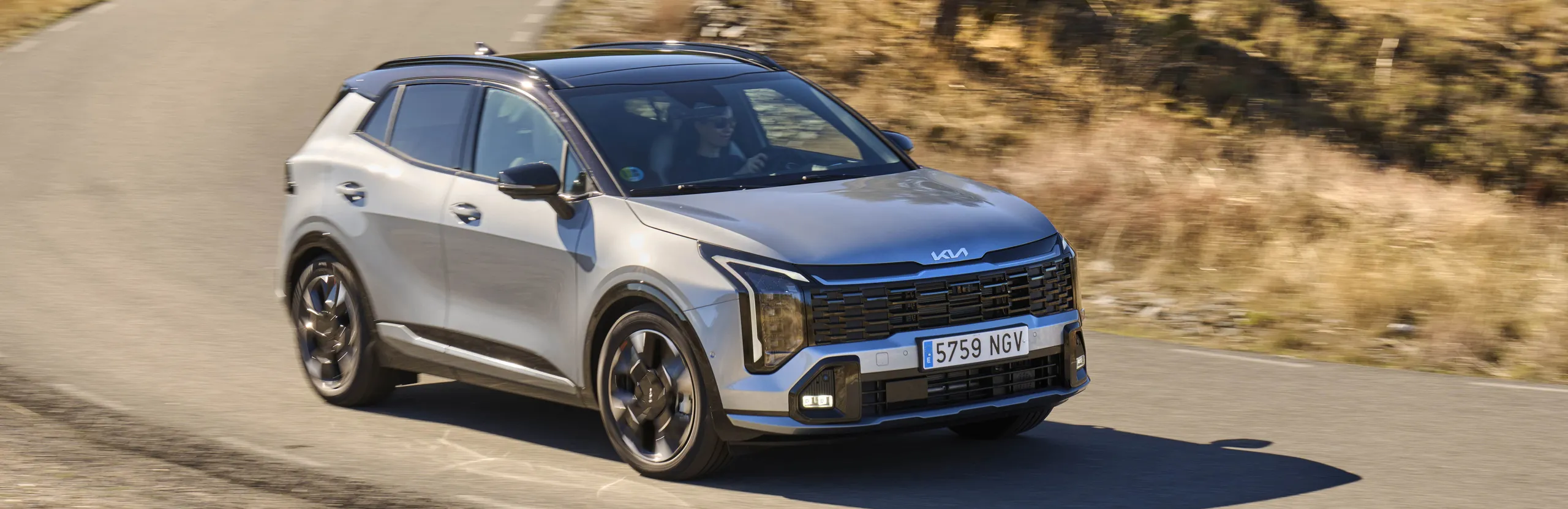 Kia Sportage blanco circulando por carretera de montaña, referencia de calidad y precio