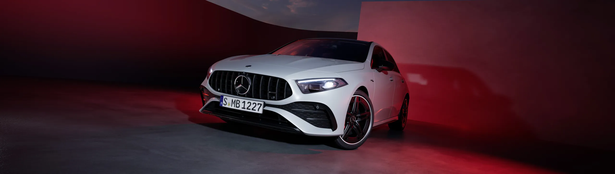 Mercedes Clase A blanco con detalles negros y llantas rojas en ambiente de estudio