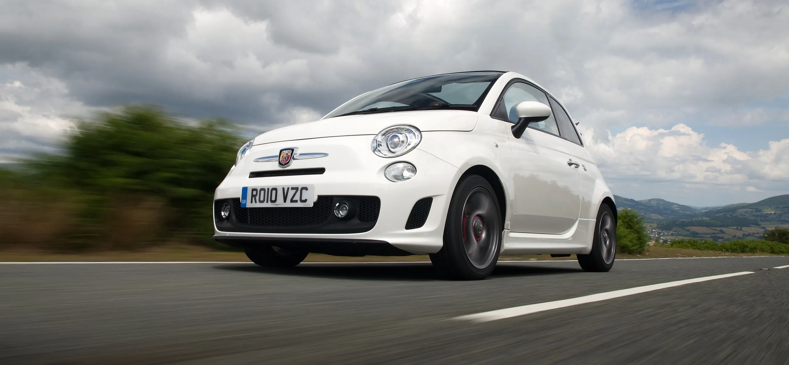 Fiat 500 Abarth blanco circulando por carretera con paisaje montañoso