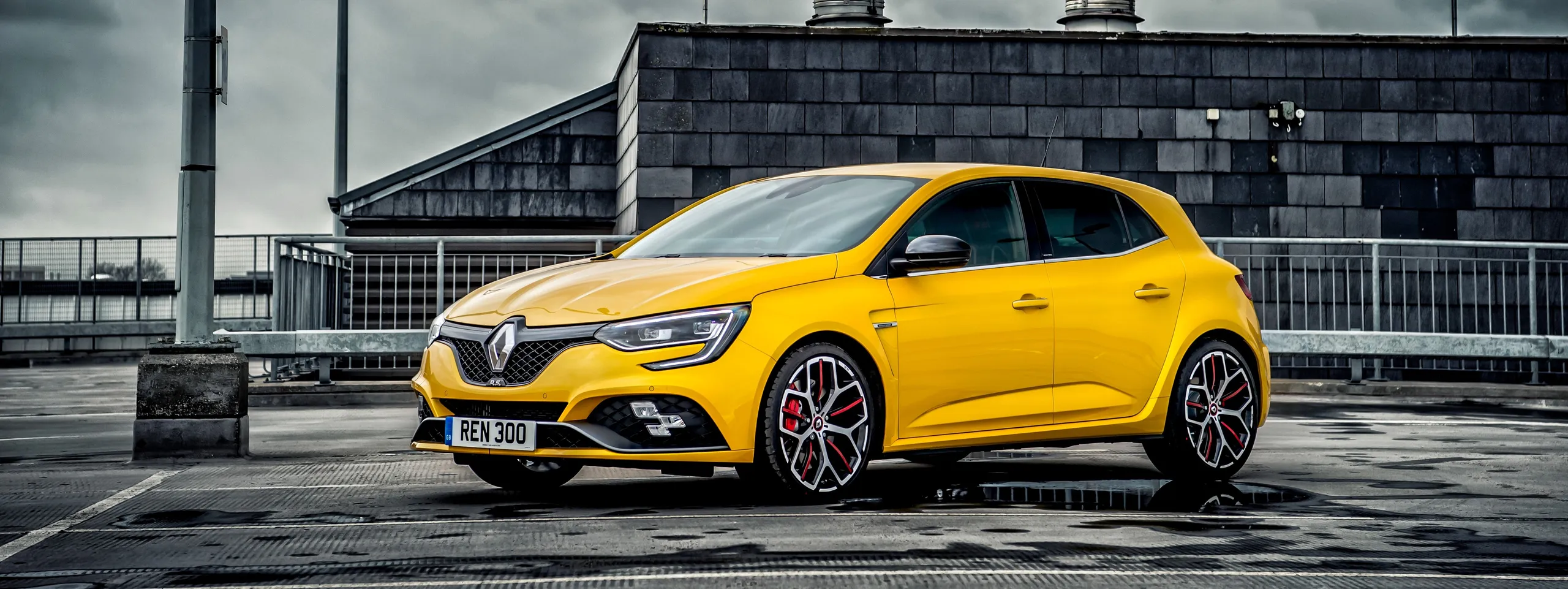 Renault Mégane RS amarillo aparcado en explanada, ejemplo de coche compacto deportivo