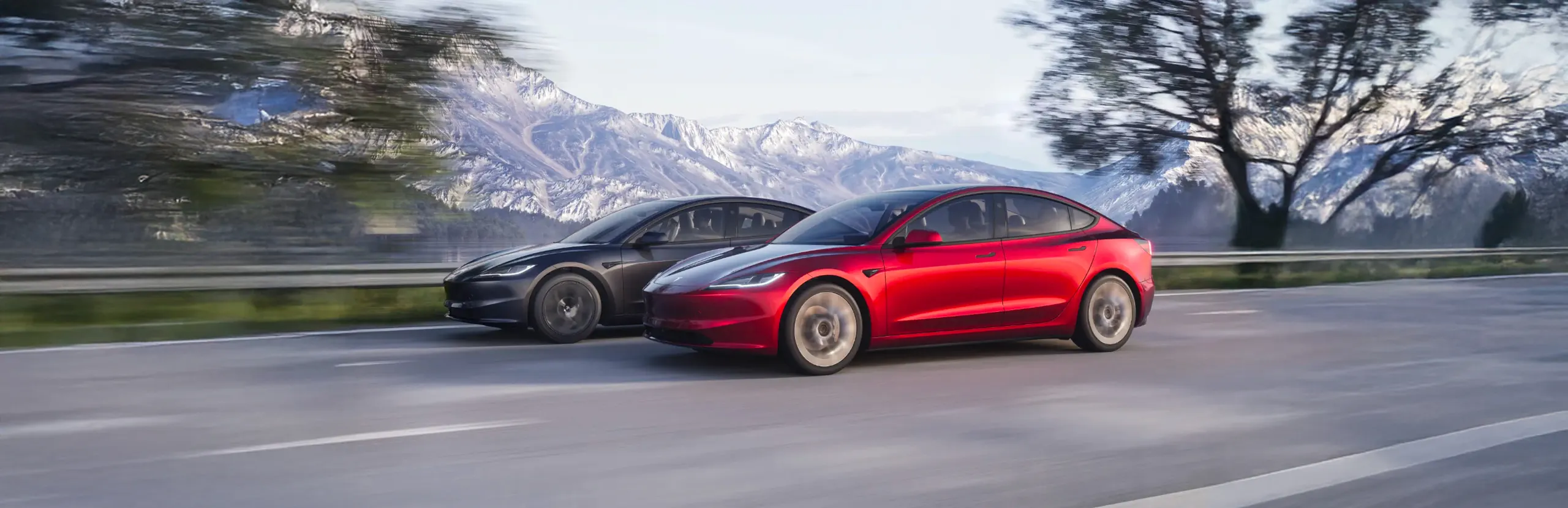 Dos coches eléctricos modernos circulando por carretera con montañas nevadas