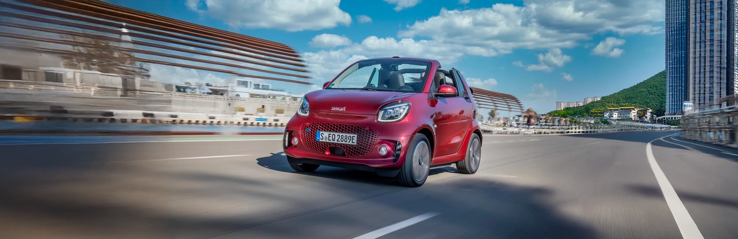 Smart eléctrico rojo circulando por autopista en entorno urbano moderno