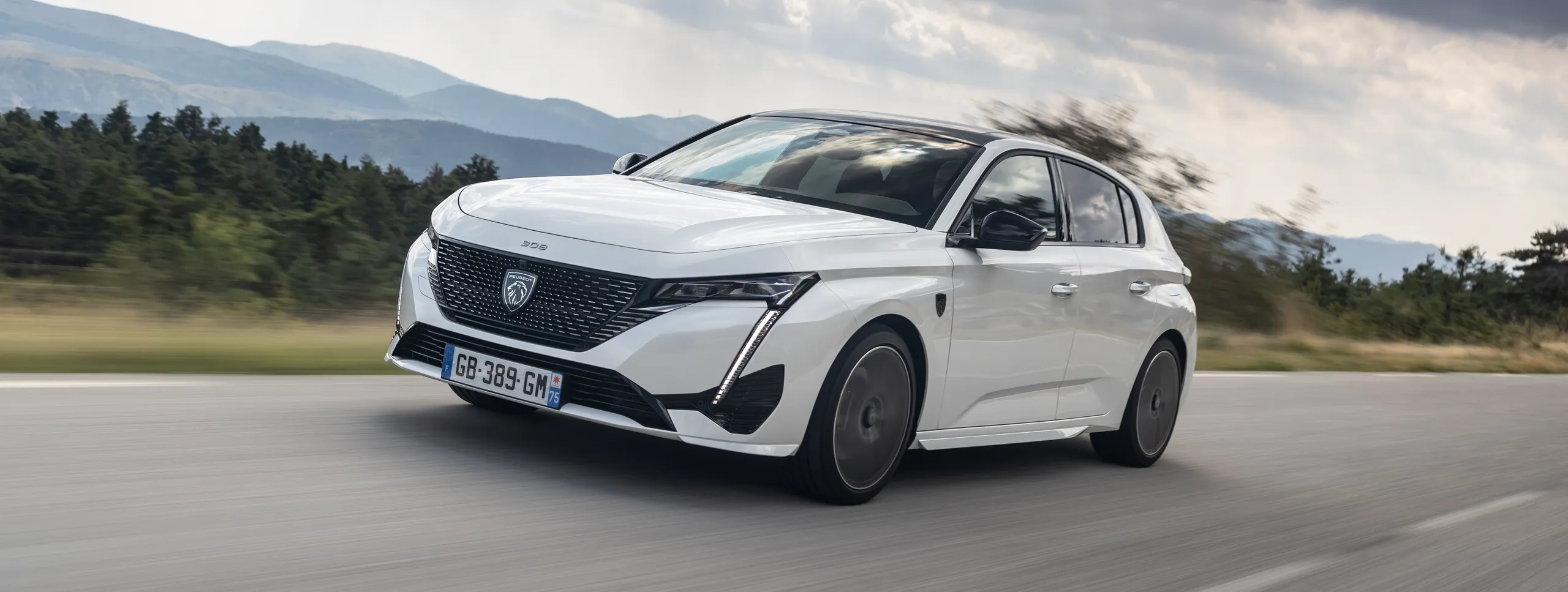Peugeot 308 SW blanco en movimiento en carretera con montañas al fondo