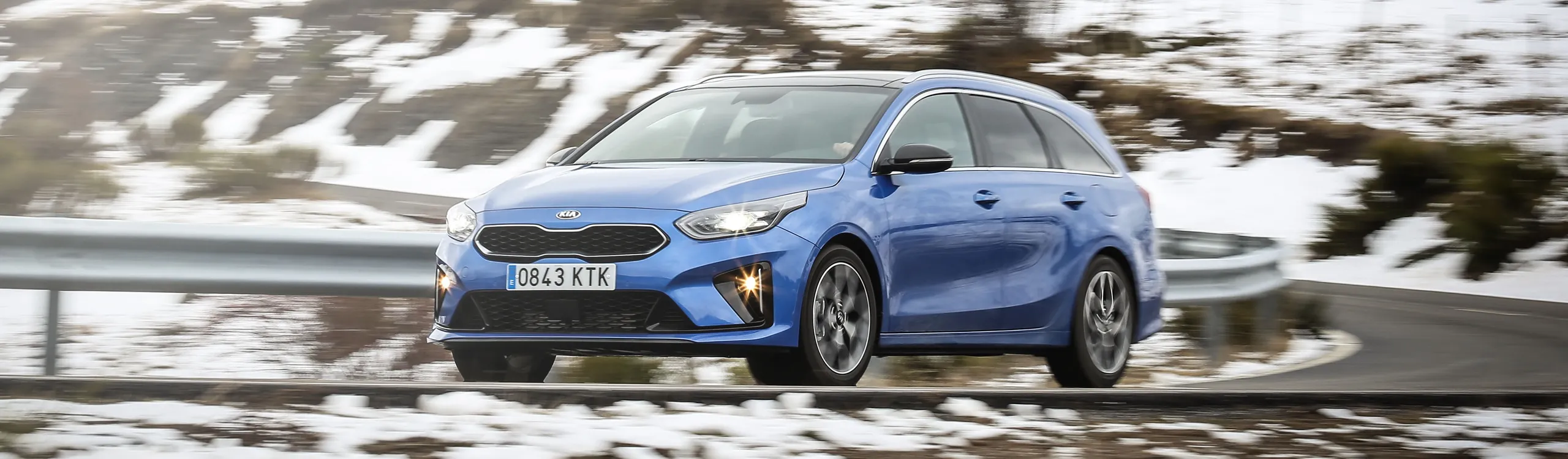 Kia Ceed Tourer azul en movimiento por carretera nevada