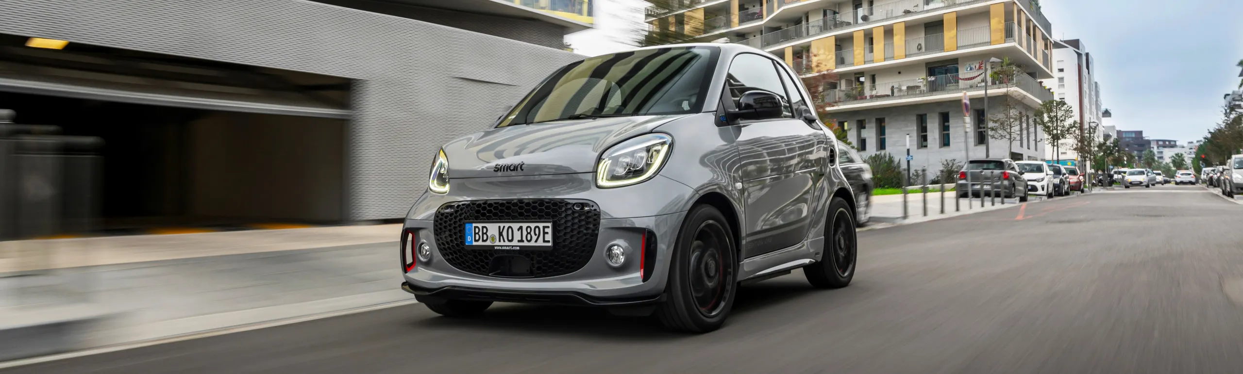 Smart ForTwo eléctrico gris en circulación por calle urbana moderna