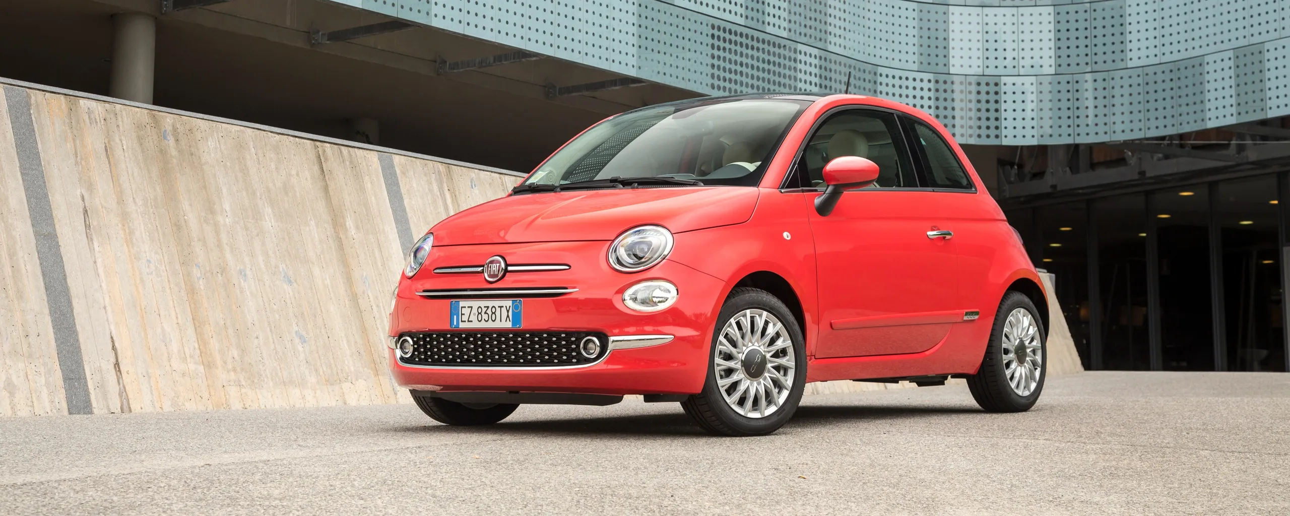 Fiat 500 rojo aparcado en garterraín urbano con diseño compacto