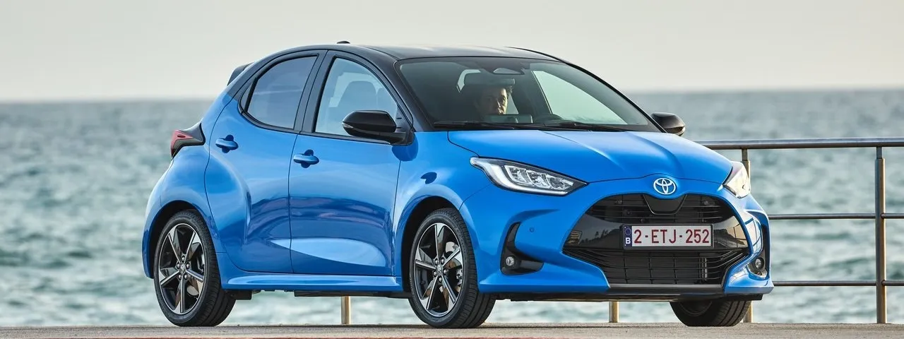 Toyota Yaris azul de segunda mano, pequeño utilitario práctico visto de perfil junto