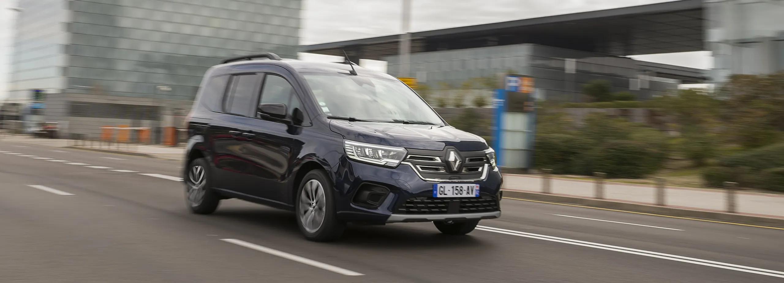 Renault Kangoo eléctrica azul marino circulando por carretera urbana bajo viaducto