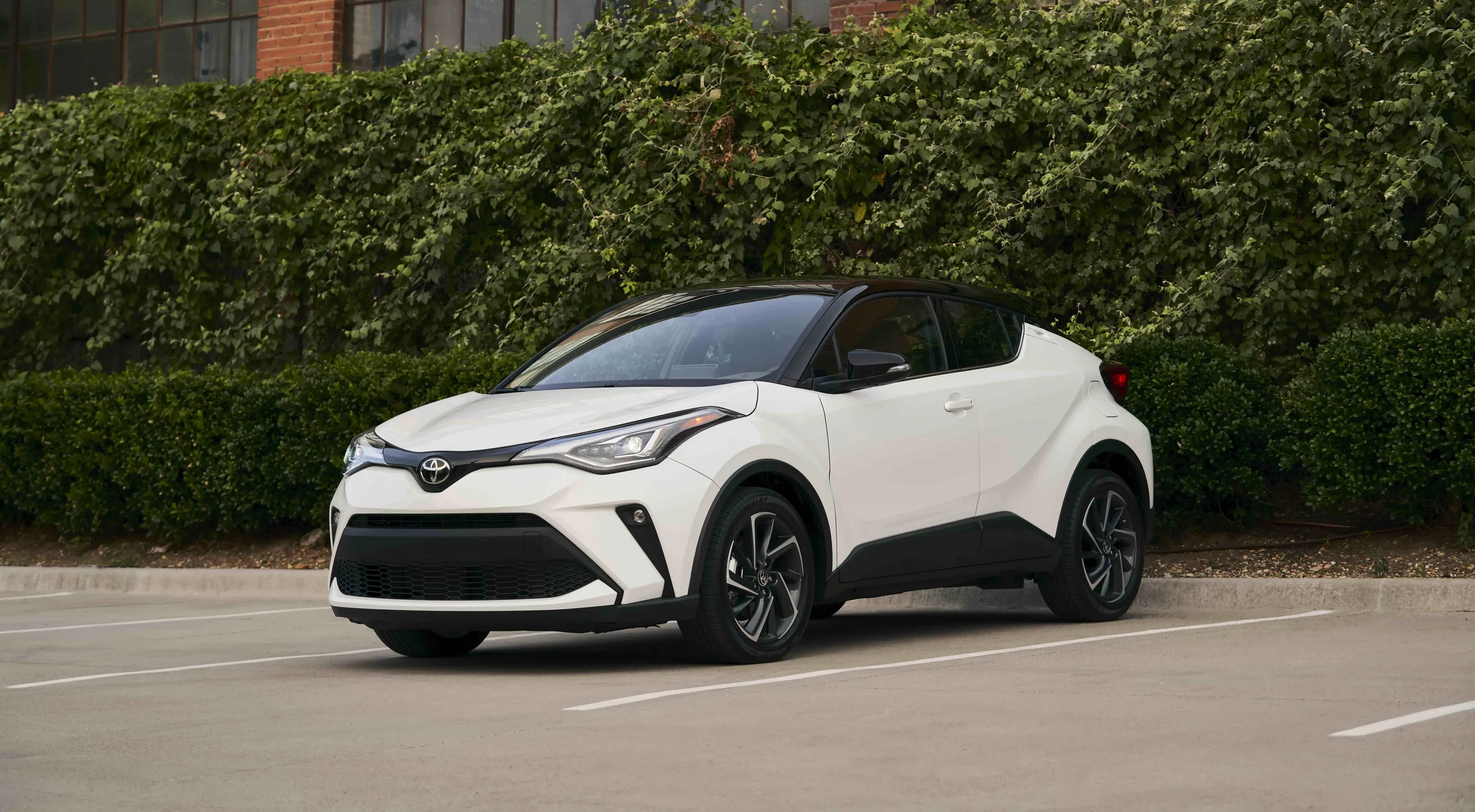 Toyota C-HR híbrido enchufable blanco en parking, vista lateral completa