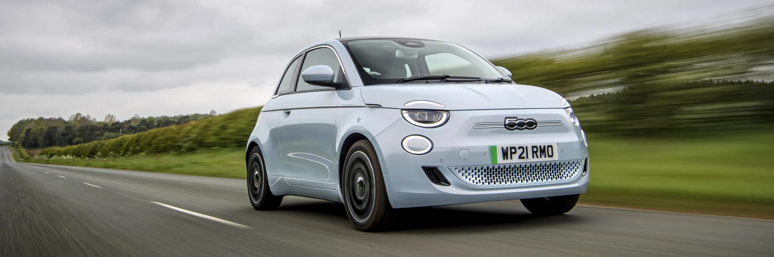 Fiat 500e blanco circulando por carretera, ejemplo de coche económico para jóvenes
