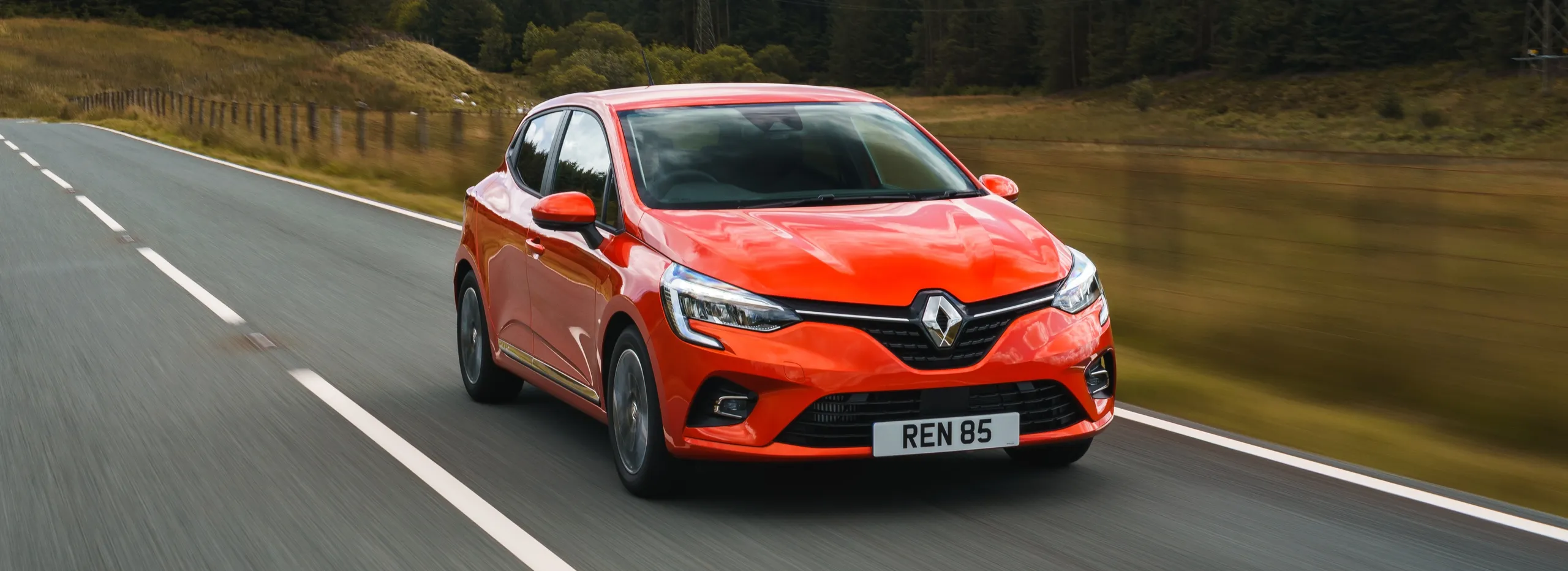 Renault Clio rojo circulando por carretera, coche compacto ideal para jóvenes conductores