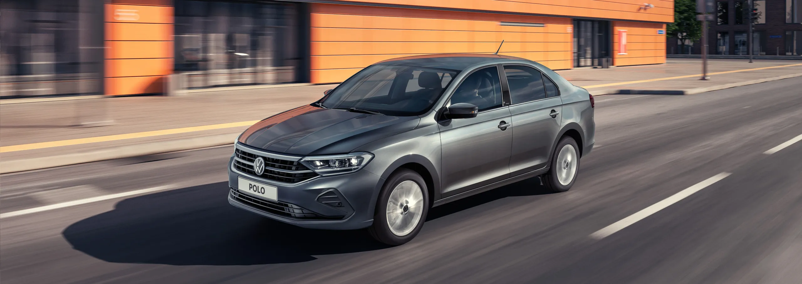 Volkswagen Polo gris circulando por una calle urbana moderna